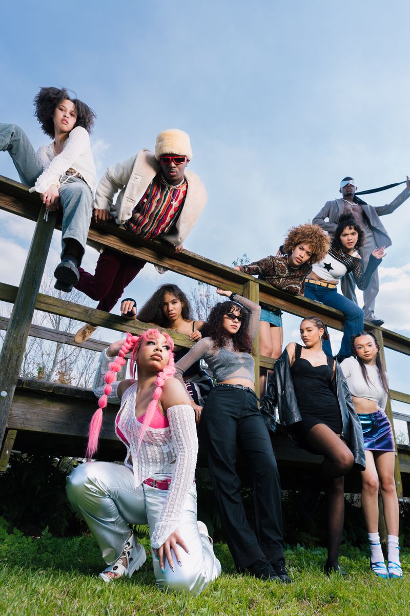 A group of young creators posing on a boardwalk, shot from below against a blue sky