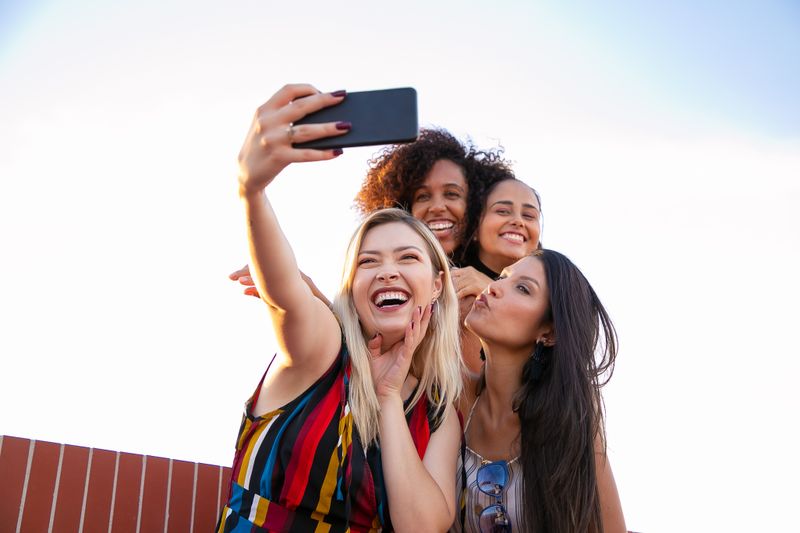Friends laughing while taking a selfie on a sunny day
